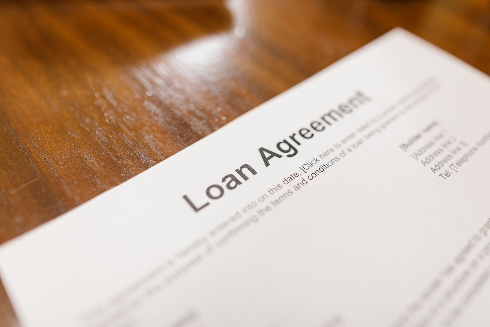 Close-up of a signed loan agreement on a wooden desk, representative of the first-lien contracts backing the fund