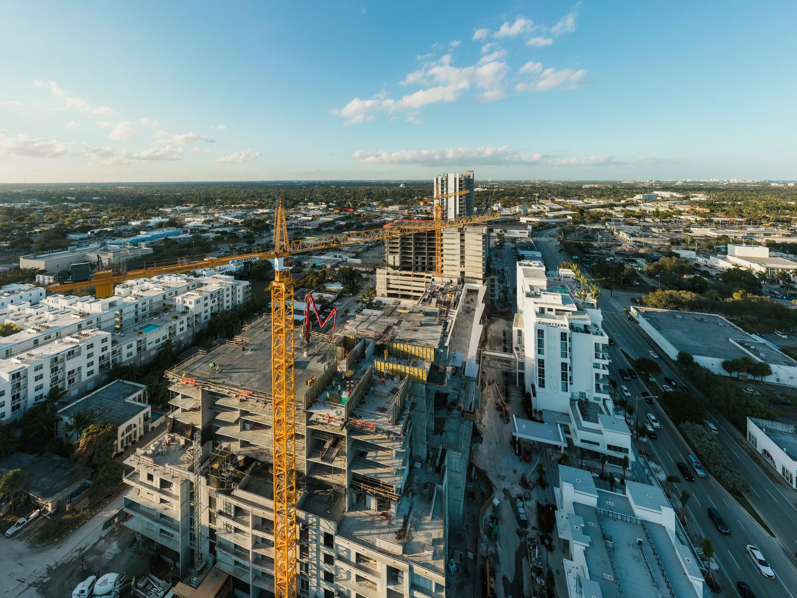 Aerial view of a multifamily construction site with a tower crane in a Florida urban district