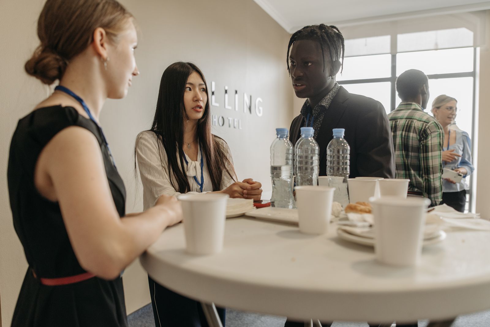 Attendees networking around a cocktail table with badges and refreshments at a business event