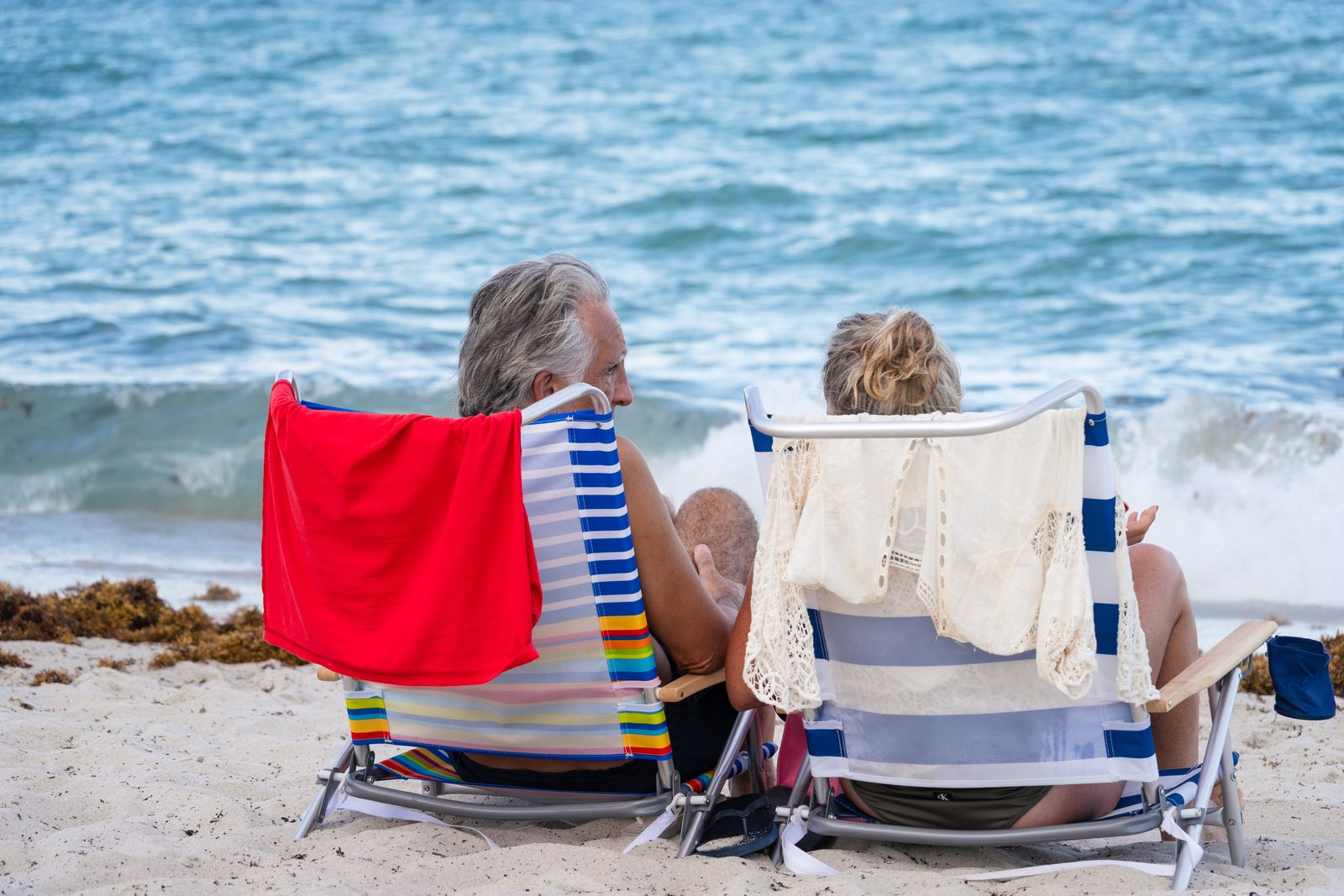 Mature couple relaxing in beach chairs looking out at the ocean, representing passive-income lifestyle
