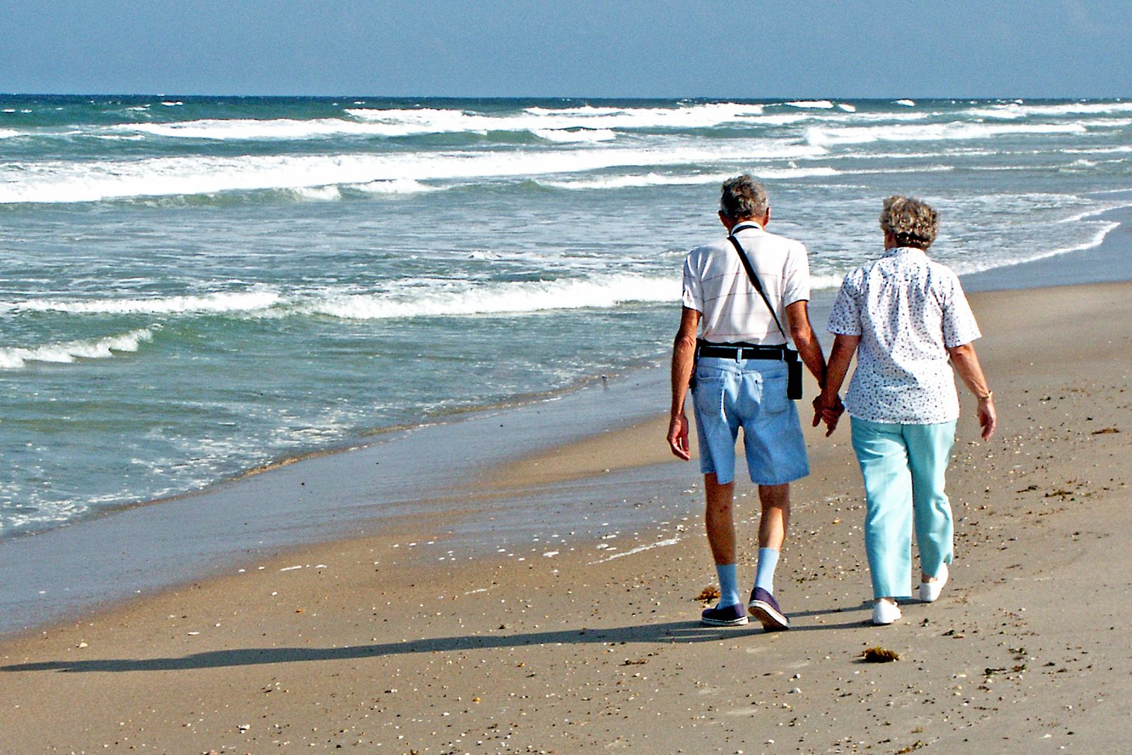 A retired couple walking along a Florida shoreline together