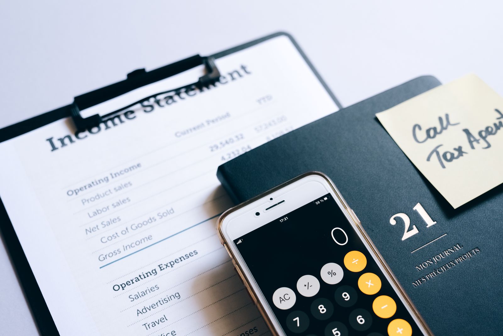 An income statement, mobile calculator, and a Call Tax Agent note on a professional planner, representing tax-year retirement account planning