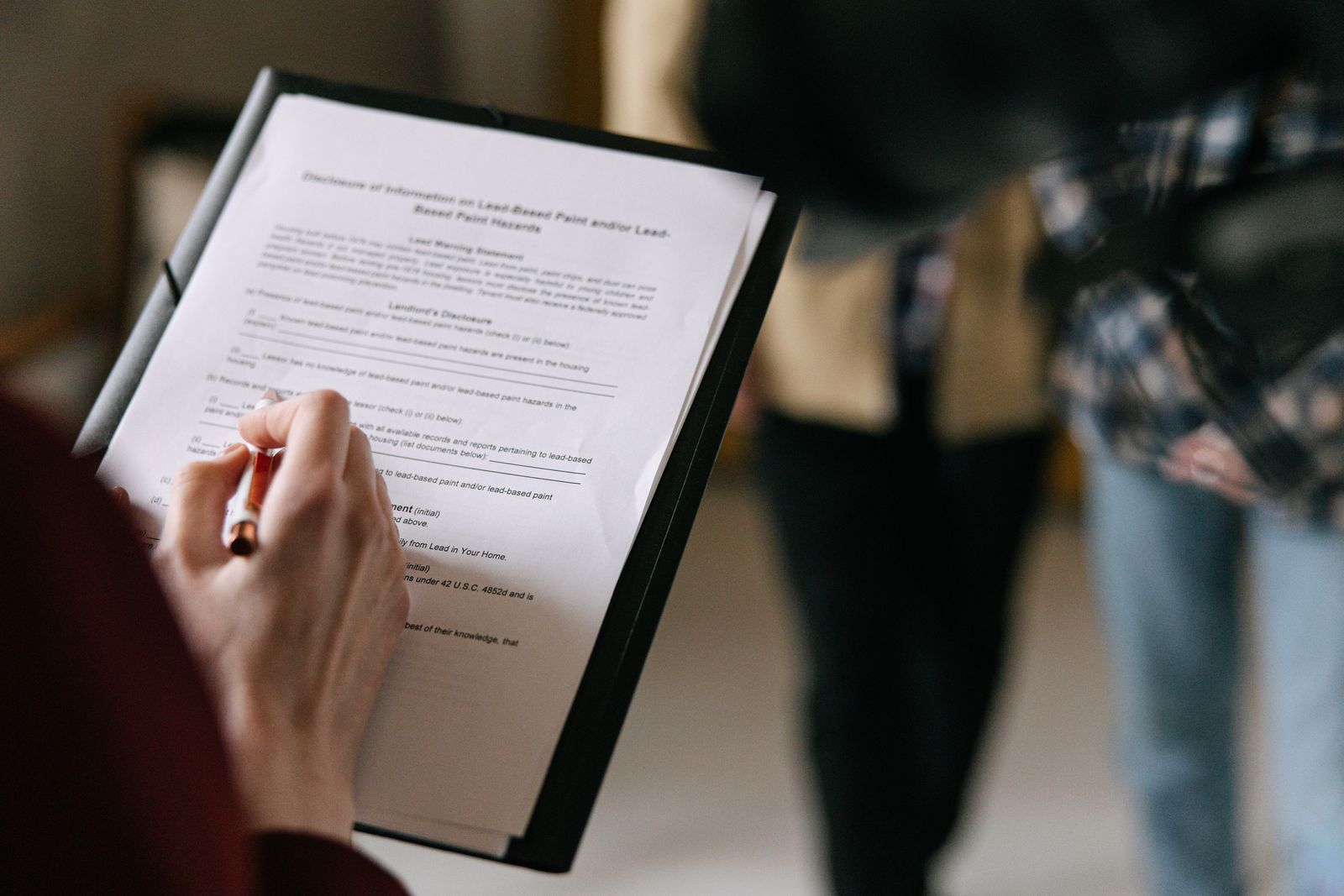 Real estate professional handing over documents to a client couple at a home closing table