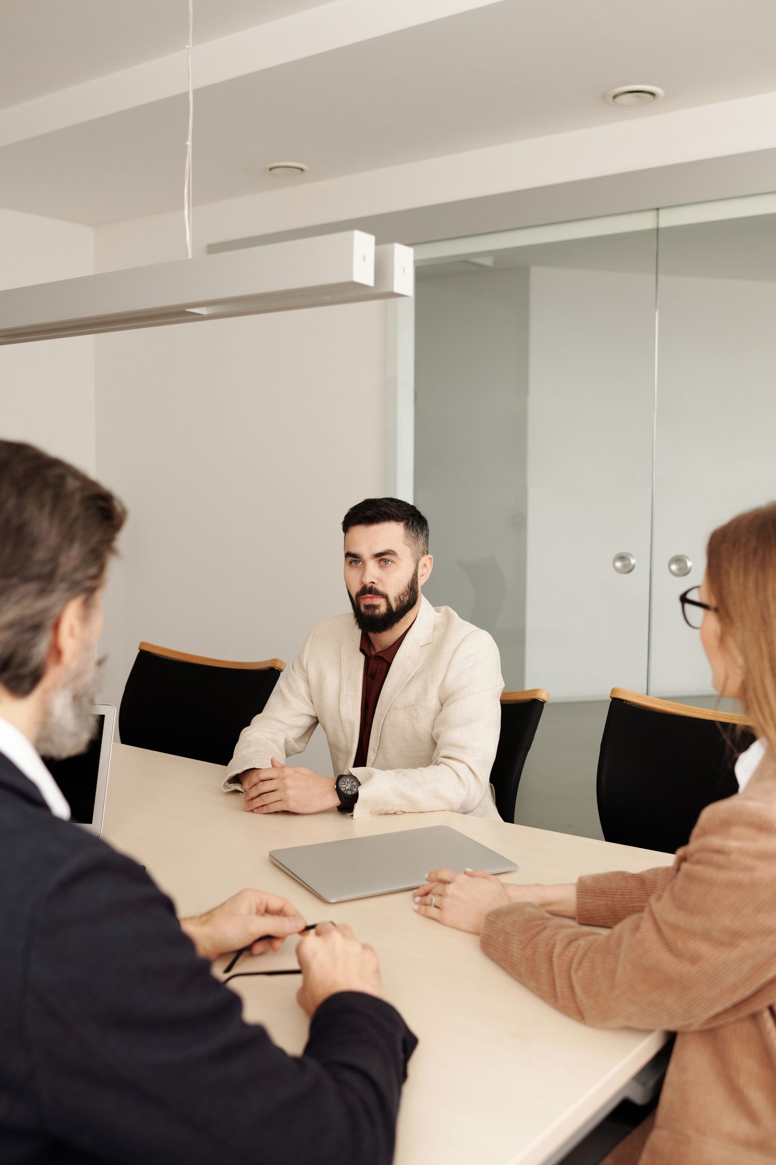 Three finance executives meeting across a boardroom table with a closed laptop