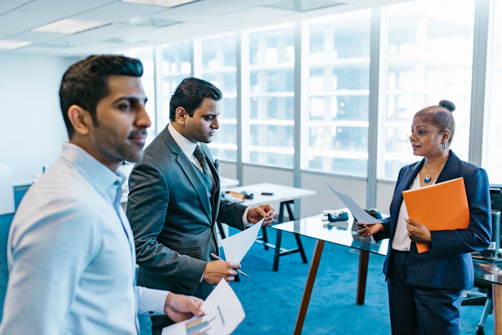 Team of investment professionals in discussion at a modern office lobby with skyline views